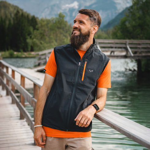 Jogger lehnt sich gegen ein Geländer auf einer Holzbrücke an einem Fluss