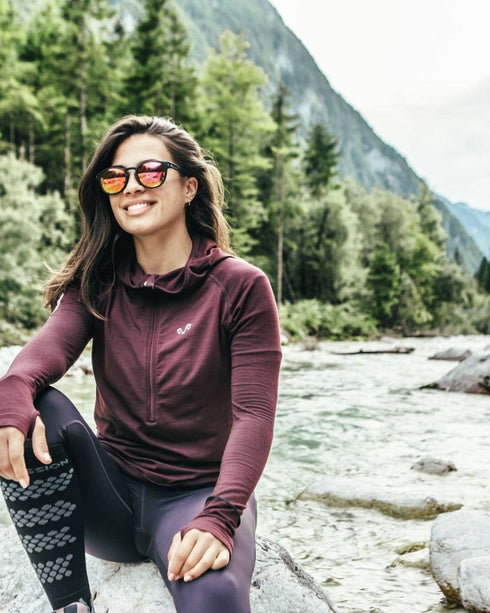 Frau mit Merino Langarmshirt mit ReiĂverschluss in Pflaume am Fluss in den Bergen